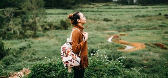 Lady with a backpack enjoying silence in the middle of a field