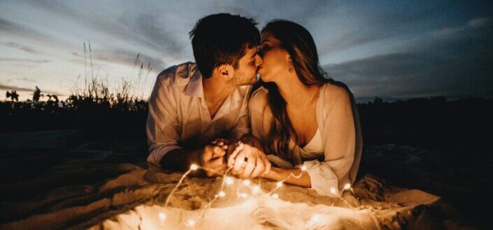 couple kissing while laying in a sand