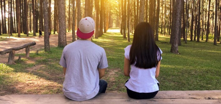 Couple sitting on a bench in a wooden park.