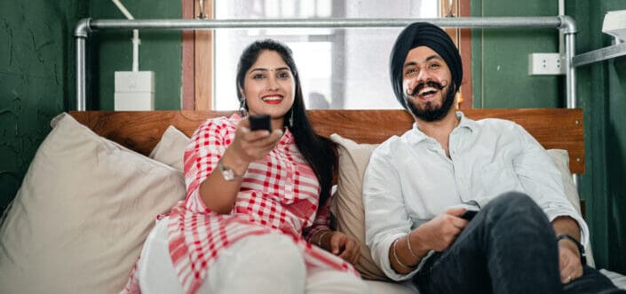 Couple watching a movie together while sitting on a couch.