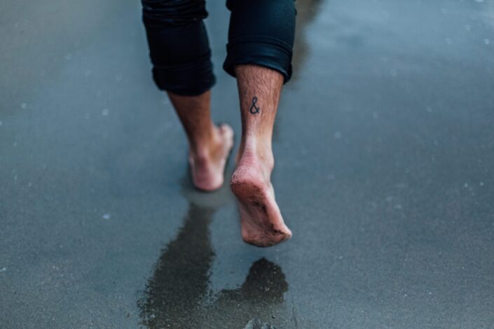 person with tattoo on foot walking bare