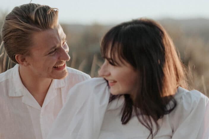 Couple in white laughing together in grassfield