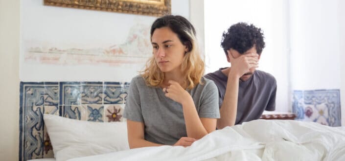 couple sitting in bed looking disappointed