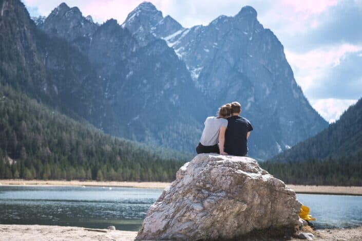 Couple sitting on a rock beside a river.