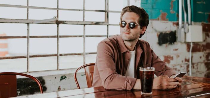 Man with sunglasses looking away while having a drink 