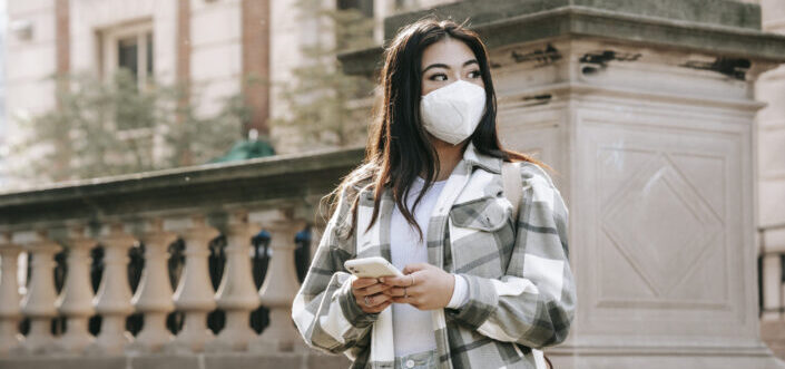 Woman wearing face mask looking away while texting.