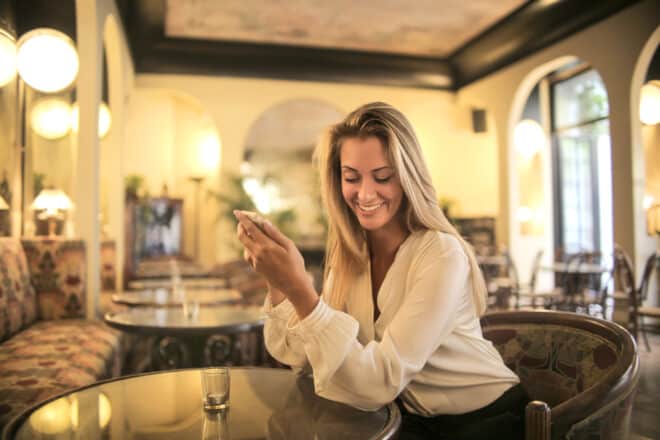 Woman sitting in a restaurant, texting - Romantic things to say to your boyfriend in a text