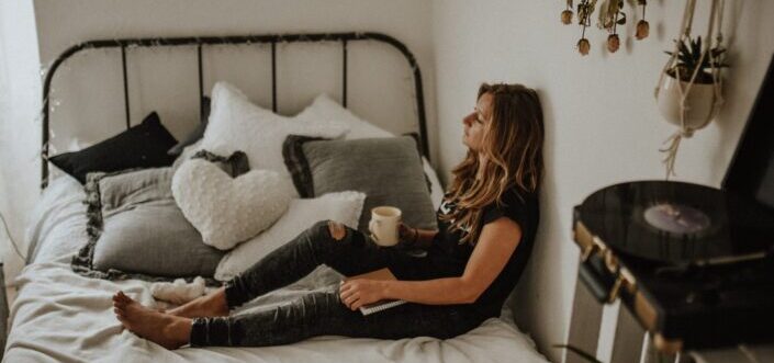 Woman thinking while having coffee in bed.