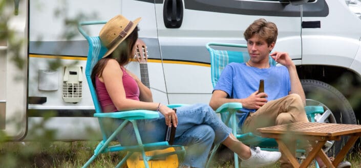 Couple chilling outside their camping van while drinking beer