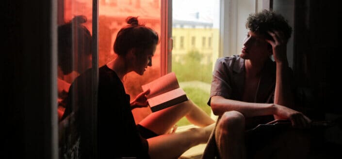 Couple reading books while they are sitting beside the window