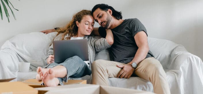 Girl with her laptop while sitting with her boyfriend on a couch