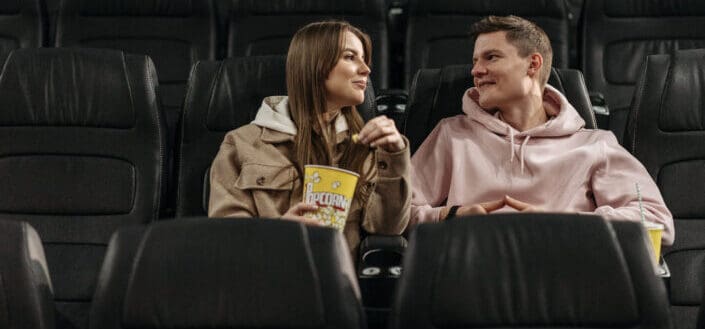Couple Eating Popcorn While Sitting in Movie Theater