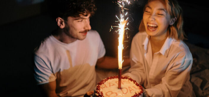 Couple Holding a Birthday Cake With Sparkling Candle