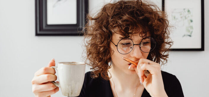 woman with eyeglasses holding her coffee while thinking