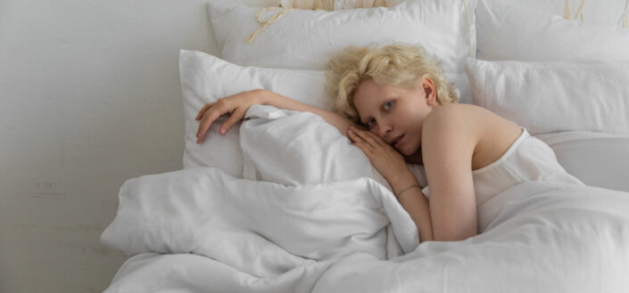 Blonde woman lying in an all white beddings