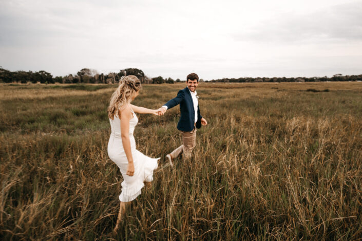 Couple in a date outfit happily running in a field 
