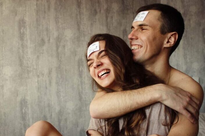 Couple Hugging and Laughing With Sticky Notes on Their Forehead