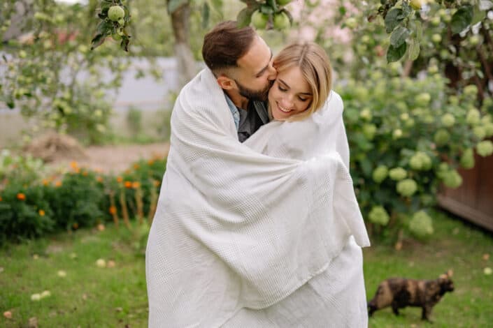 A man kissing a woman while wrapped in a blanket