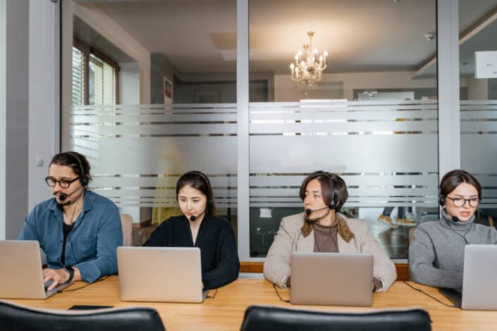 Multiracial employees sitting in front of silver laptops