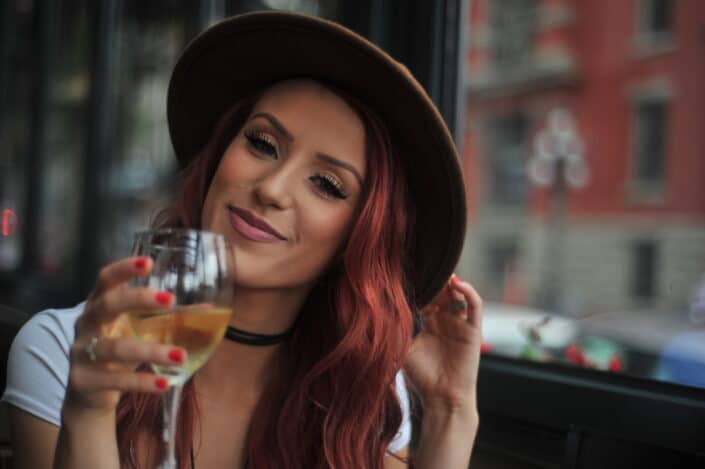 Portrait photo of a woman holding wine glass near a glass window