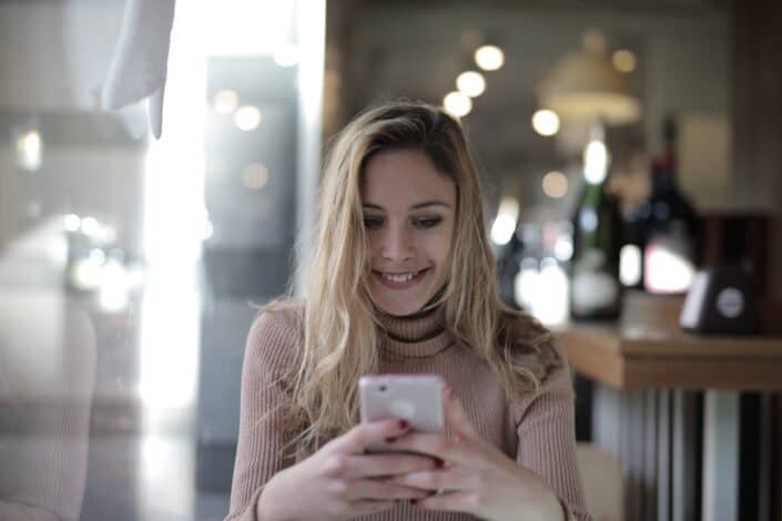 Woman in brown knit sweater holding white smartphone