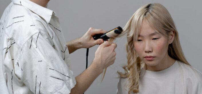 Man Using Curler on a Woman's Hair
