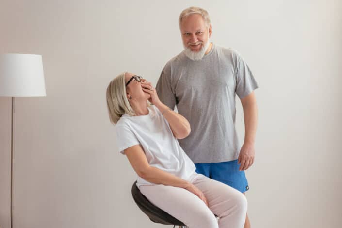 Woman sitting on a stool laughing at his husband