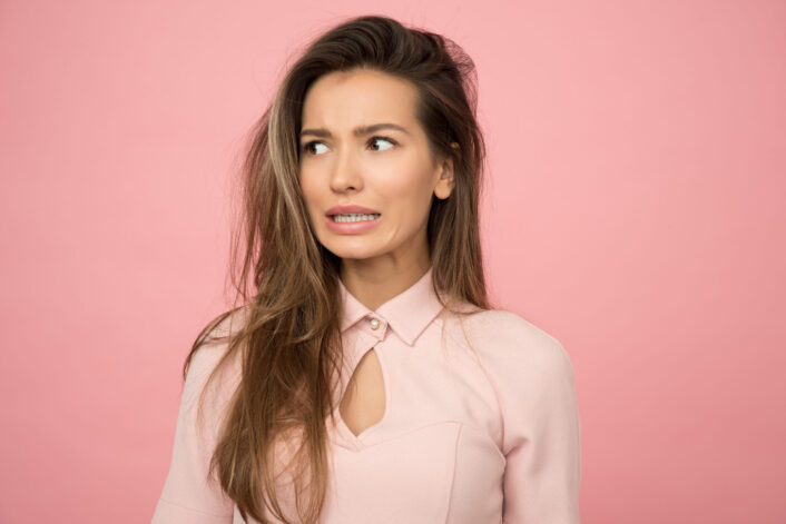 Woman with disgusted face on a pink background