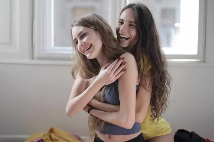 Laughing Girlfriends Hugging in Living Room