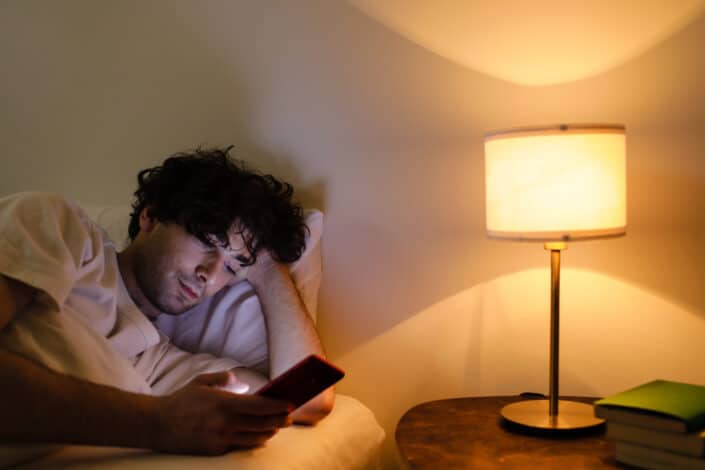 A man using his smartphone while in bed