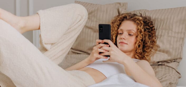 A woman using her smartphone in bed