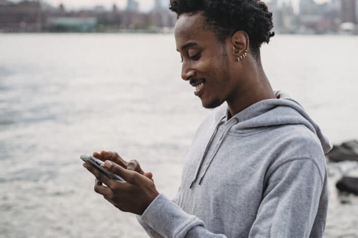man messaging on smartphone on embankment
