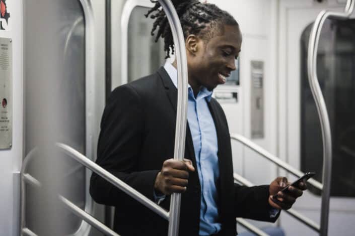 Cheerful black man surfing net on mobile on subway train