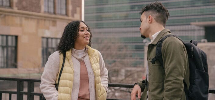 Cheerful hispanic couple talking on urban street