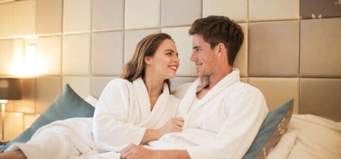 a couple relaxing on bed in bathrobes