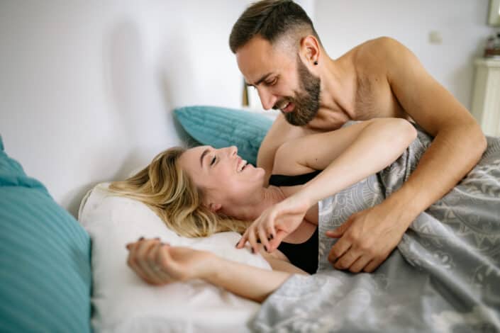 Couple Lying in Bed and Smiling