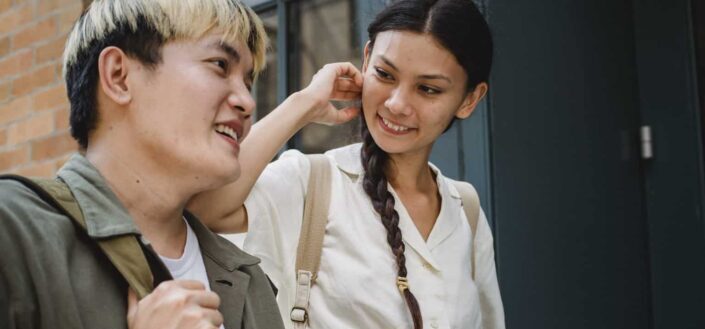 Crop cheerful asian couple chatting near building entrance