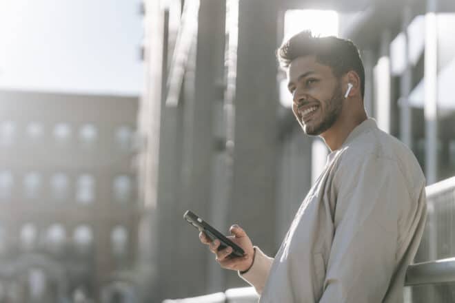 Happy man using his phone on street - Flirty Texts To Make Him Laugh