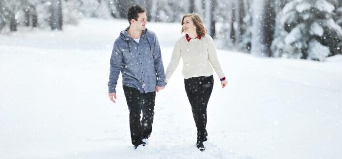 a couple walking in the snow while holding hands