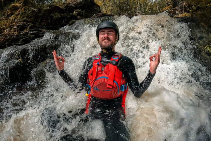 Man in a raging waterfalls with his eyes closed