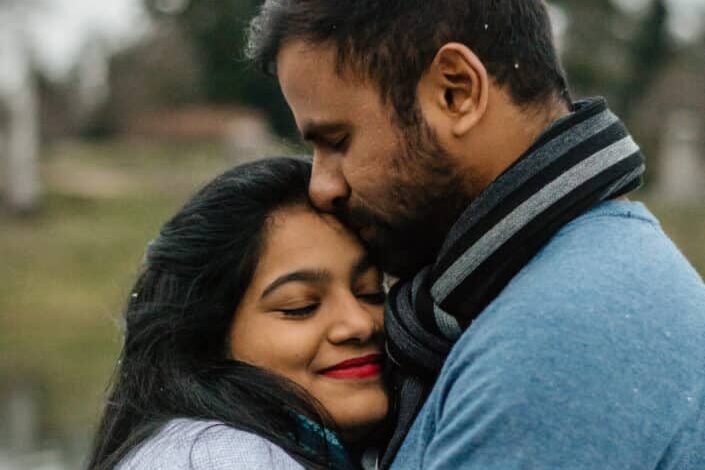 Man in blue kissing woman on forehead