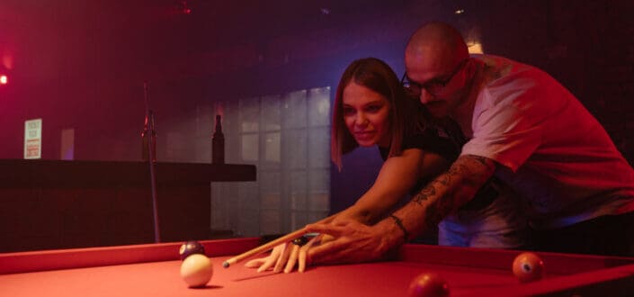 Man Teaching a Woman Play Billiards