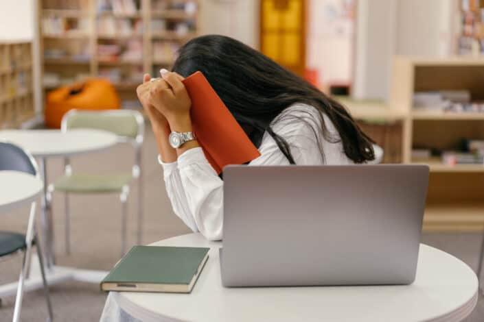 Woman covering her face with a notebook