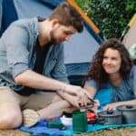 Truth or dare questions for boyfriend - Happy young couple preparing lunch during camping in forest - featured