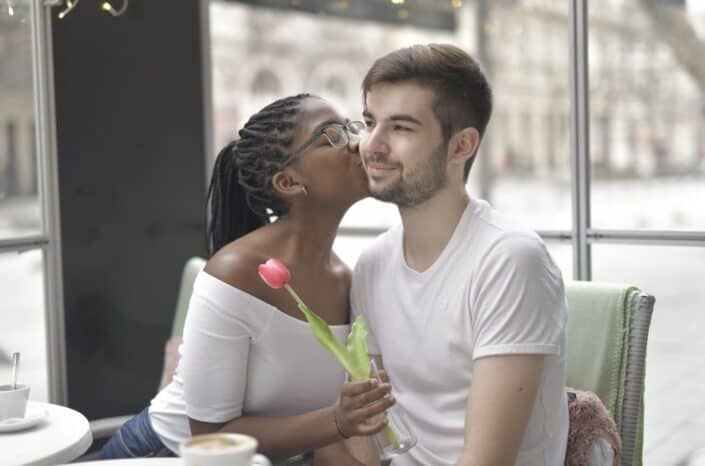 Woman holding a flower kissing a man