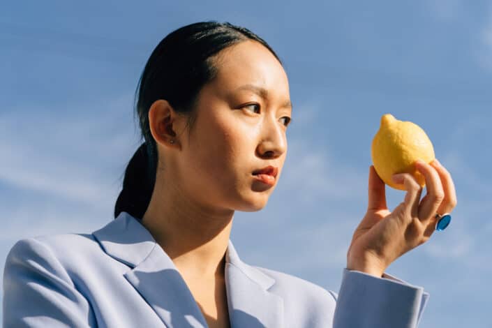 Woman in blue coat holding a lemon