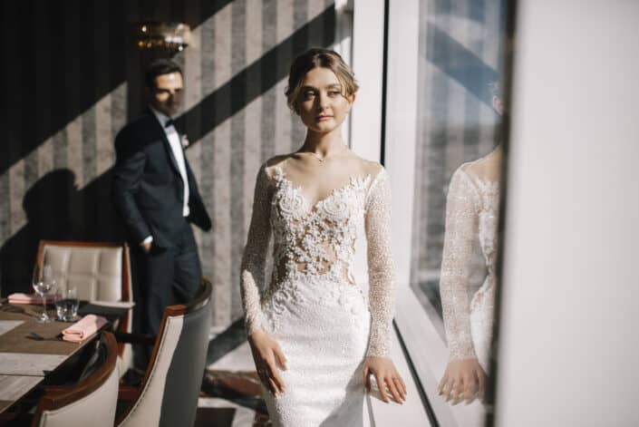 Woman in Wedding Dress Standing Beside Glass Window