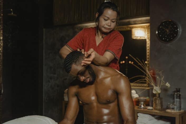 Woman massaging a shirtless man on head while sitting