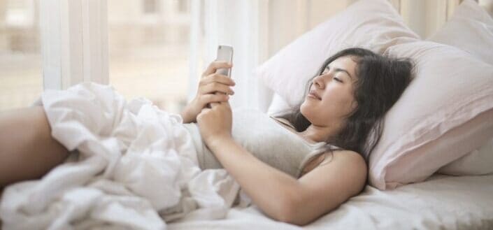 Young woman using smartphone in bed