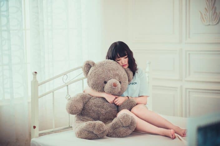 teenage girl holding a big brown bear in her room